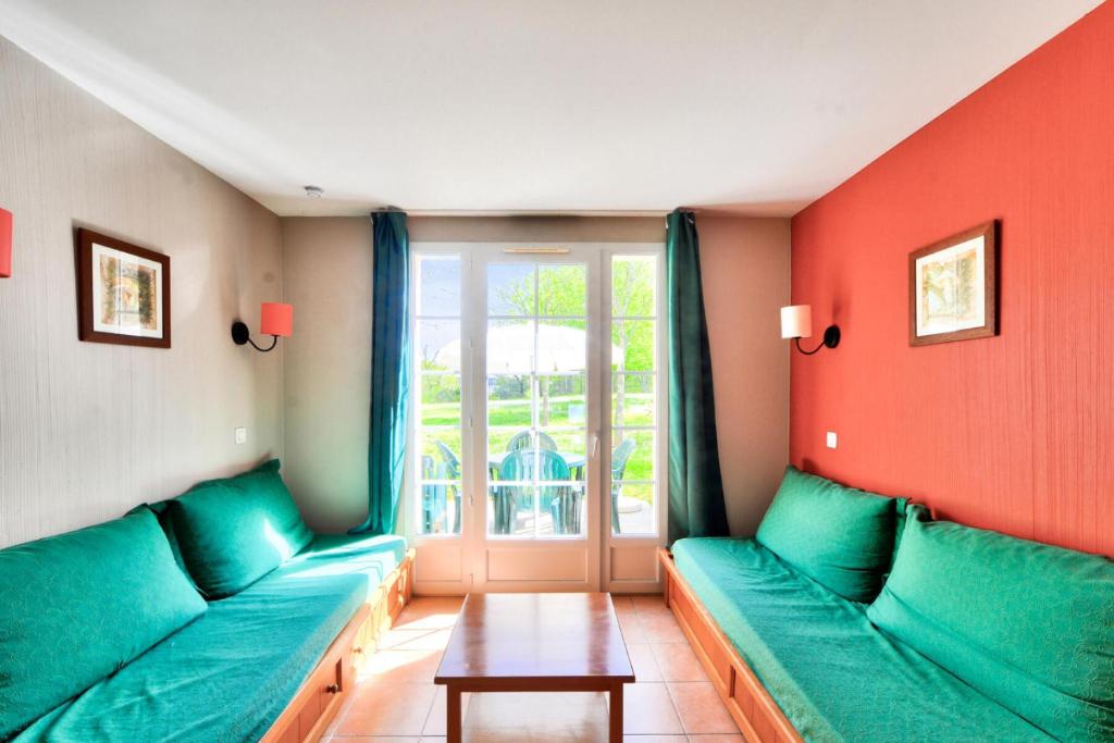 - un salon avec des canapés verts et une fenêtre dans l'établissement La résidence du Lac - maeva Home - Maison 2 pièces 5 personnes - Sélection MAE-0094, à Monflanquin