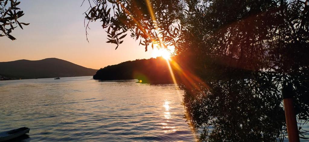 a sunset over a body of water with the sun setting at Apartment Kjara in Tivat