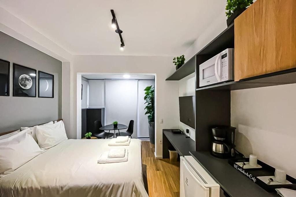 a bedroom with a bed and a desk and a kitchen at BHomy Brooklin - Novo c varanda integrada BUR102 in Sao Paulo