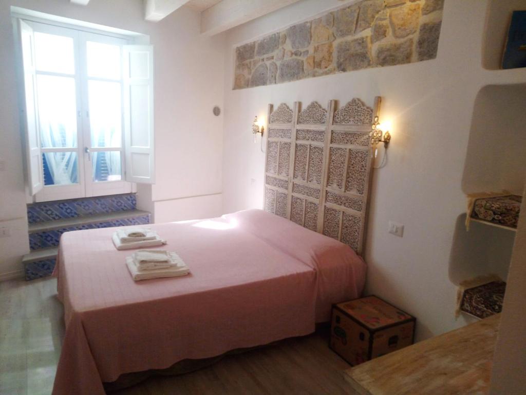 um quarto com uma cama rosa e uma janela em B&B Terra - Stanza Viaggio em Carloforte