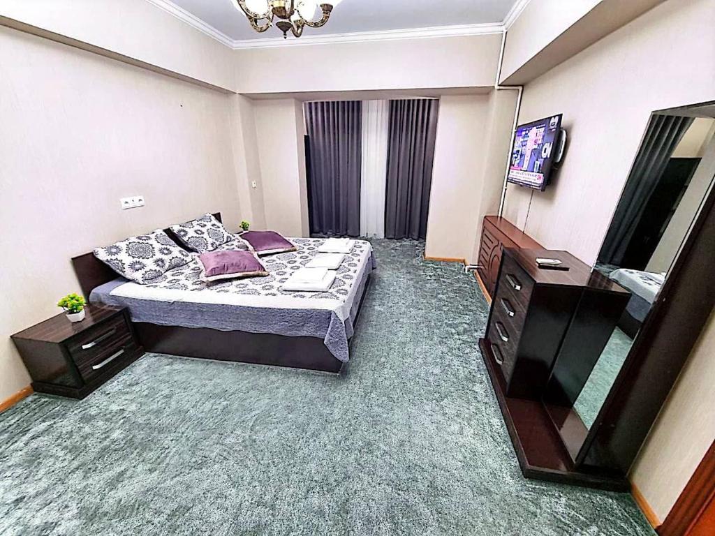 ein Schlafzimmer mit einem Bett, einer Kommode und einem TV in der Unterkunft City Center Apartment 1 in Taschkent