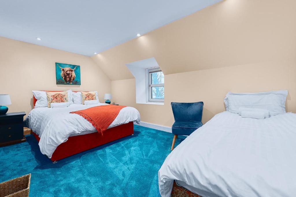 two beds in a room with blue carpet at Kinkell House B&B in Cononbridge
