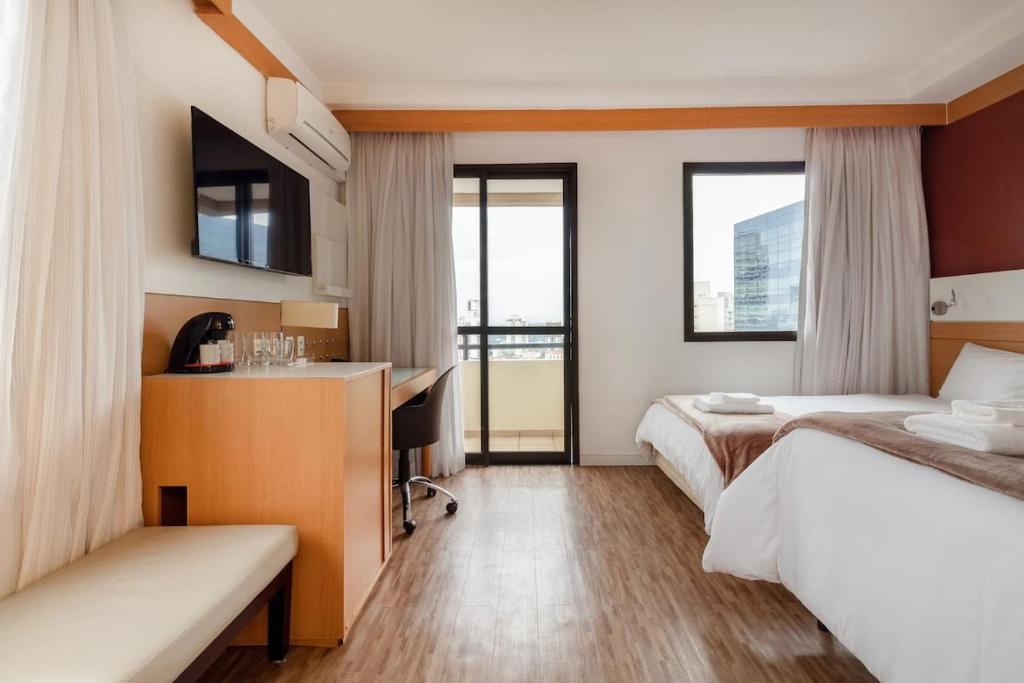 a hotel room with two beds and a desk at BHomy Pinheiros - Flat em ótima região Q1601 in Sao Paulo