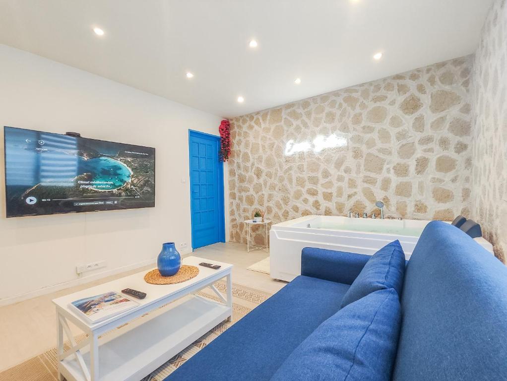 a living room with a blue couch and a tv at Évasion Santorin - Jacuzzi & Relax in Le Havre
