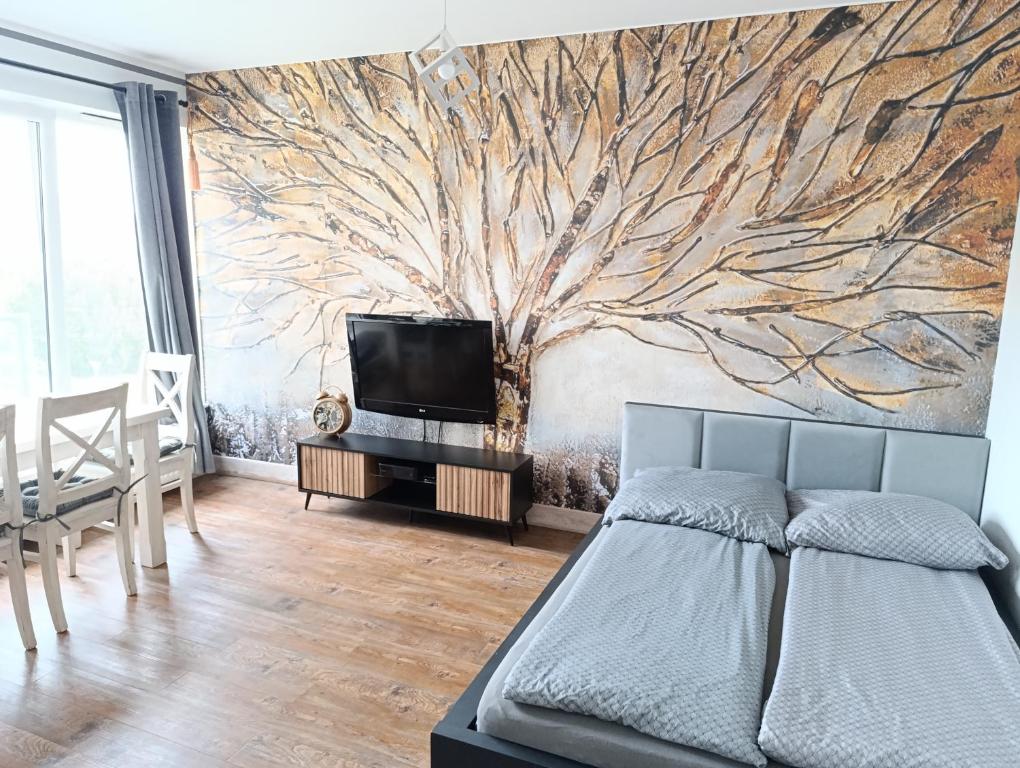 a bedroom with a tree mural on the wall at Sweet Heart Home in Szczecin