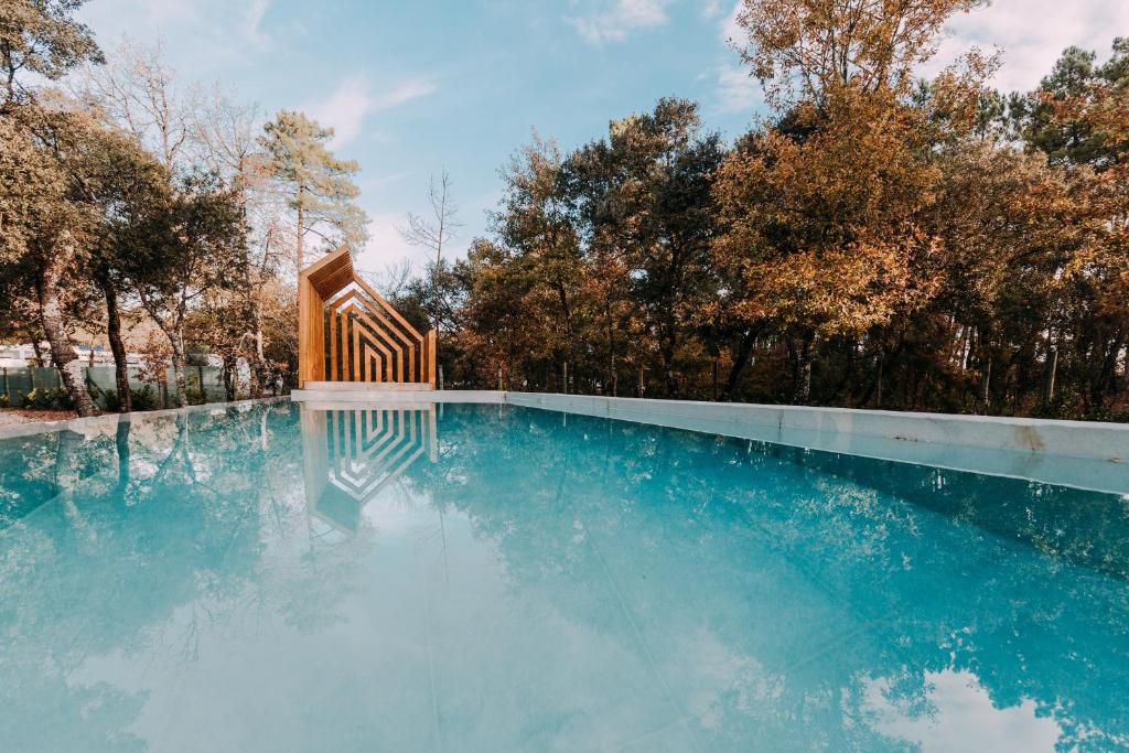 uma piscina de água com um banco de madeira em Luz Charming Houses em Fátima