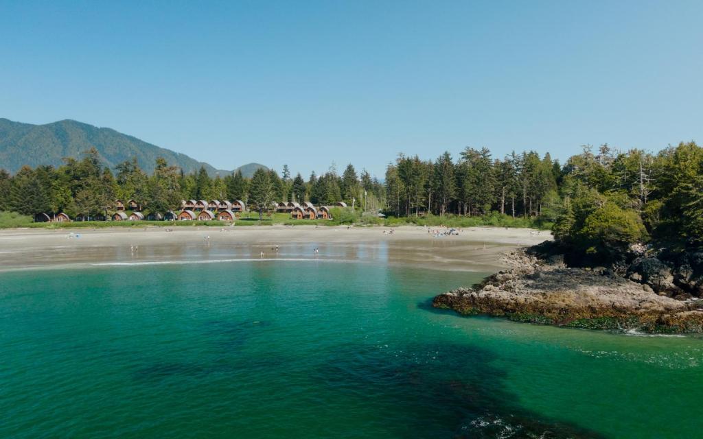 een waterlichaam met een strand en bomen bij Ocean Village Resort in Tofino