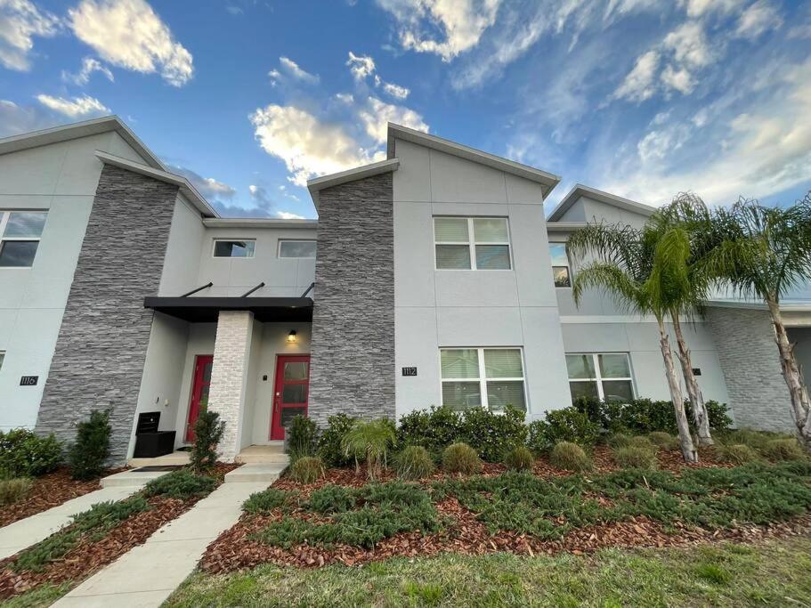 a white house with palm trees in front of it at 4BR Townhouse Private Pool BBQ Near Disney in Kissimmee