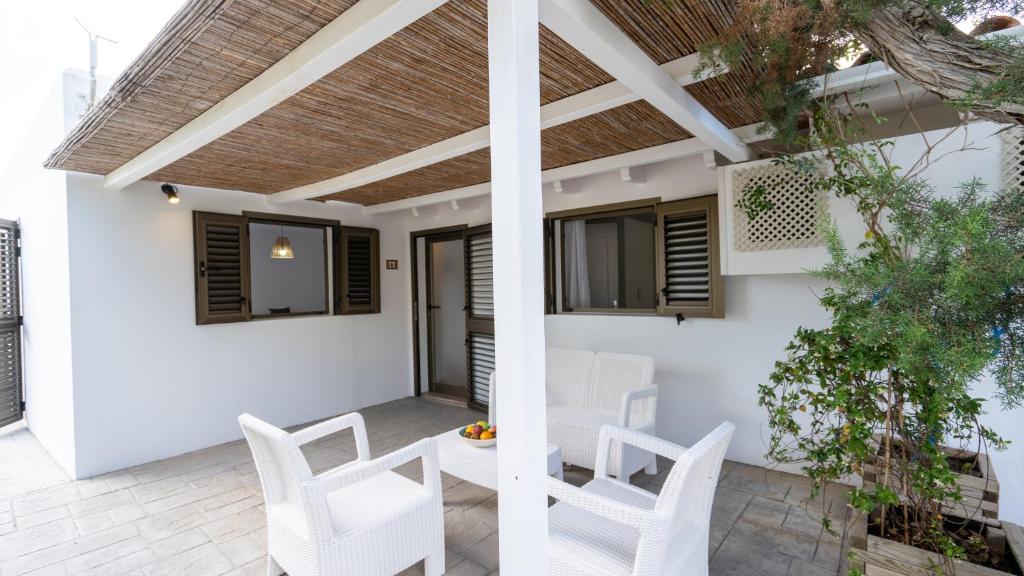 a patio with white chairs and a pergola at Hotel Rosamar - Emar Hotels in Es Pujols