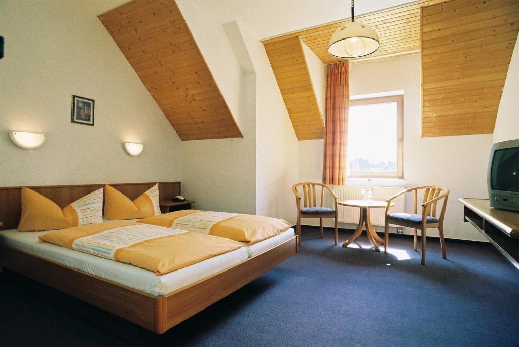 a bedroom with a bed and a table and chairs at Hotel Zum Schneekopf "Garni" in Gehlberg