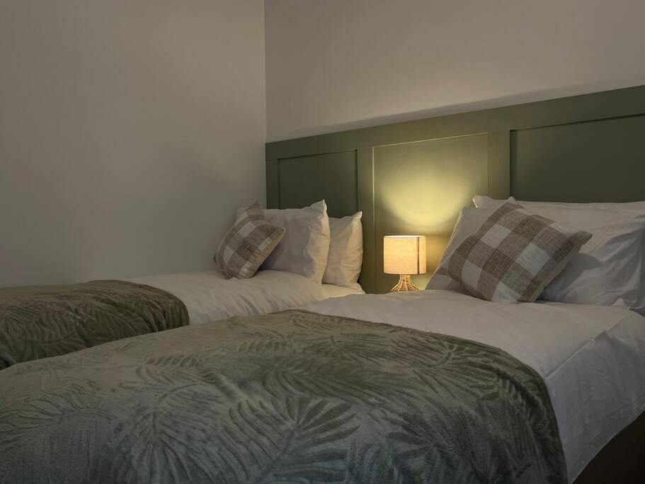1 dormitorio con 2 camas y lámpara. en NEW! 3 Bed House with Pool Table, Parking, Netflix en Nottingham