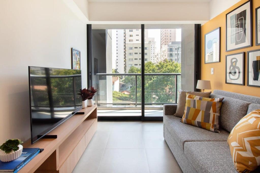 ein Wohnzimmer mit einem Sofa und einem großen Fenster in der Unterkunft BHomy Perdizes Novo e perfeito para 4 DH302 in São Paulo