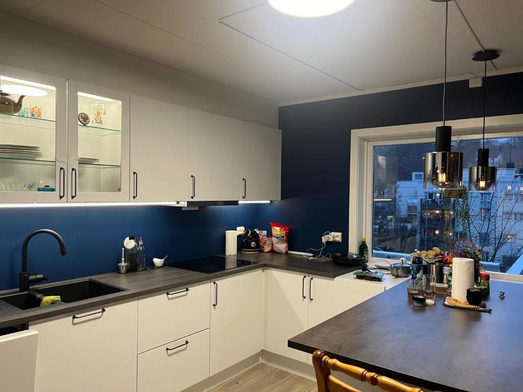 una cocina con armarios blancos y una pared azul en Arendalsuka - Fin enebolig, sentralt og sjønært,gratis parkering 4 rom 3 bad 2 stuer en Arendal