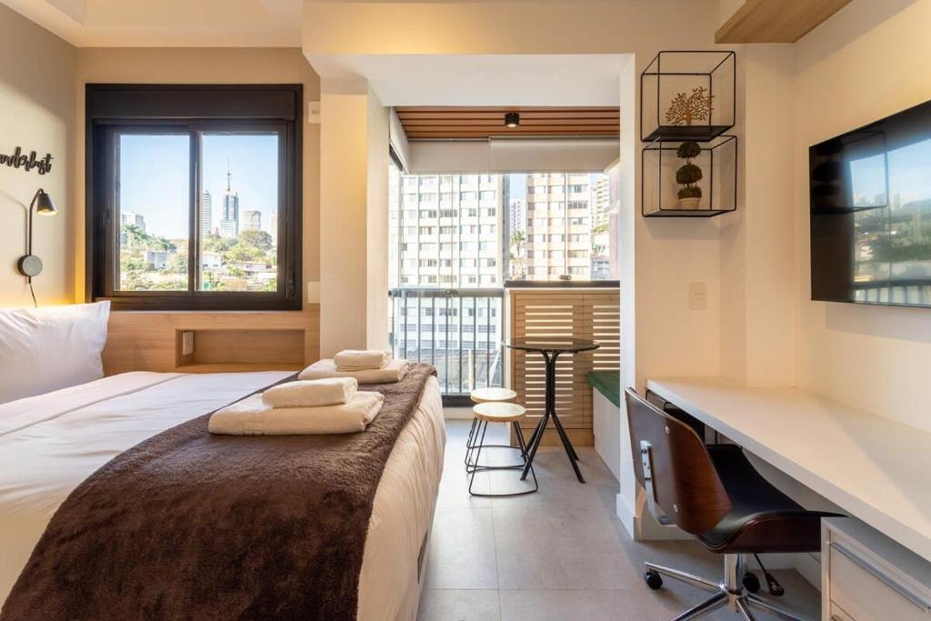 a bedroom with a bed with a desk and a balcony at BHomy VMadalena - Com vista de Sampa UP310 in São Paulo