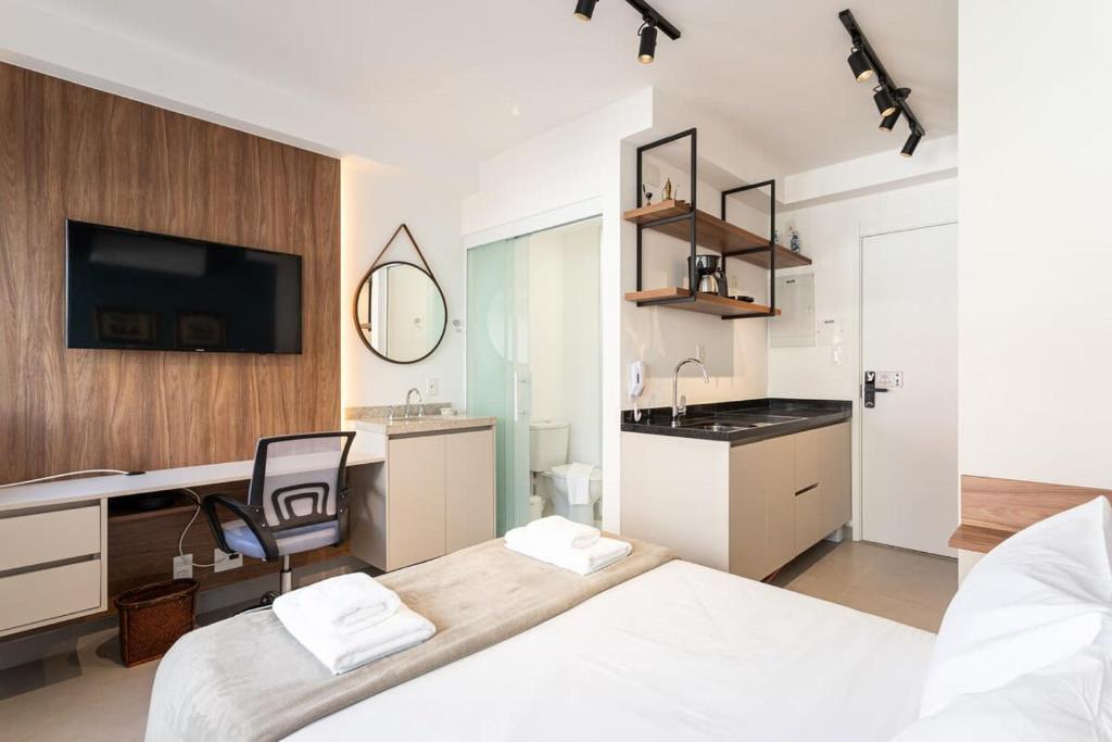 een slaapkamer met een bed en een keuken met een wastafel bij BHomy V Madalena - Studio novo e completo UP305 in Sao Paulo