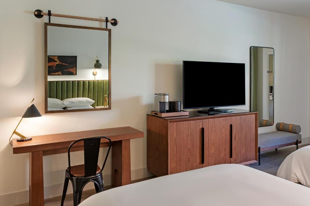 a bedroom with a television and a desk with a chair at The Red Cliffs Lodge Zion, a Tribute Portfolio Hotel in Springdale