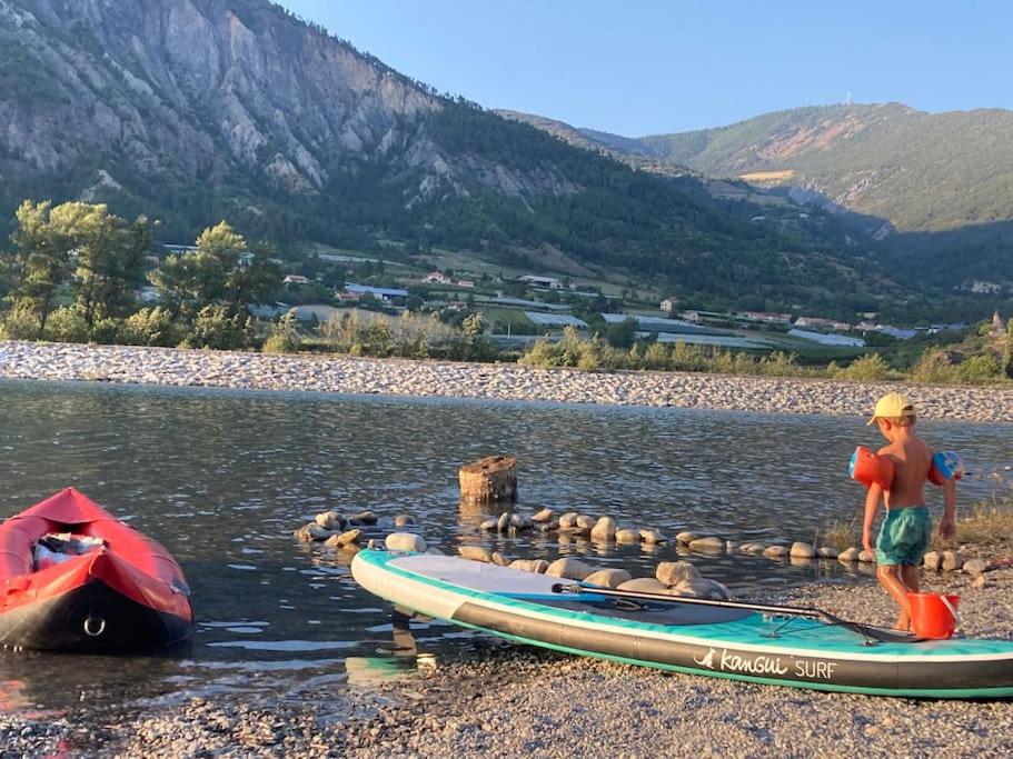 un jeune garçon debout à côté d'un bateau sur une rivière dans l'établissement mobilhome entre montagne et lac près de Gap au calme, à Rochebrune
