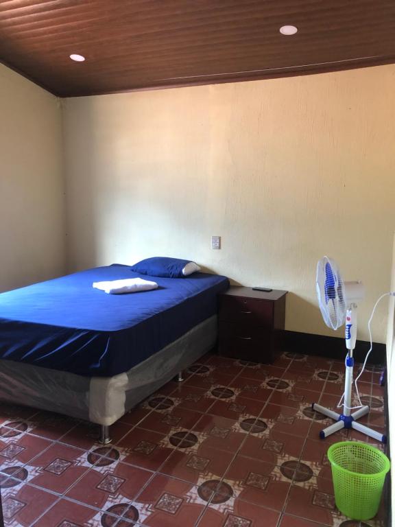 a bedroom with a bed with blue sheets and a fan at Hostal Sanjuanerita in San Juan La Laguna