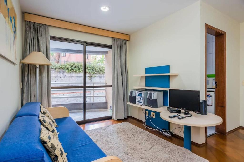 ein Wohnzimmer mit einem blauen Sofa und einem Schreibtisch mit einem Computer in der Unterkunft BHomy Bela Vista Próximo Sírio Libanês RPL308 in São Paulo