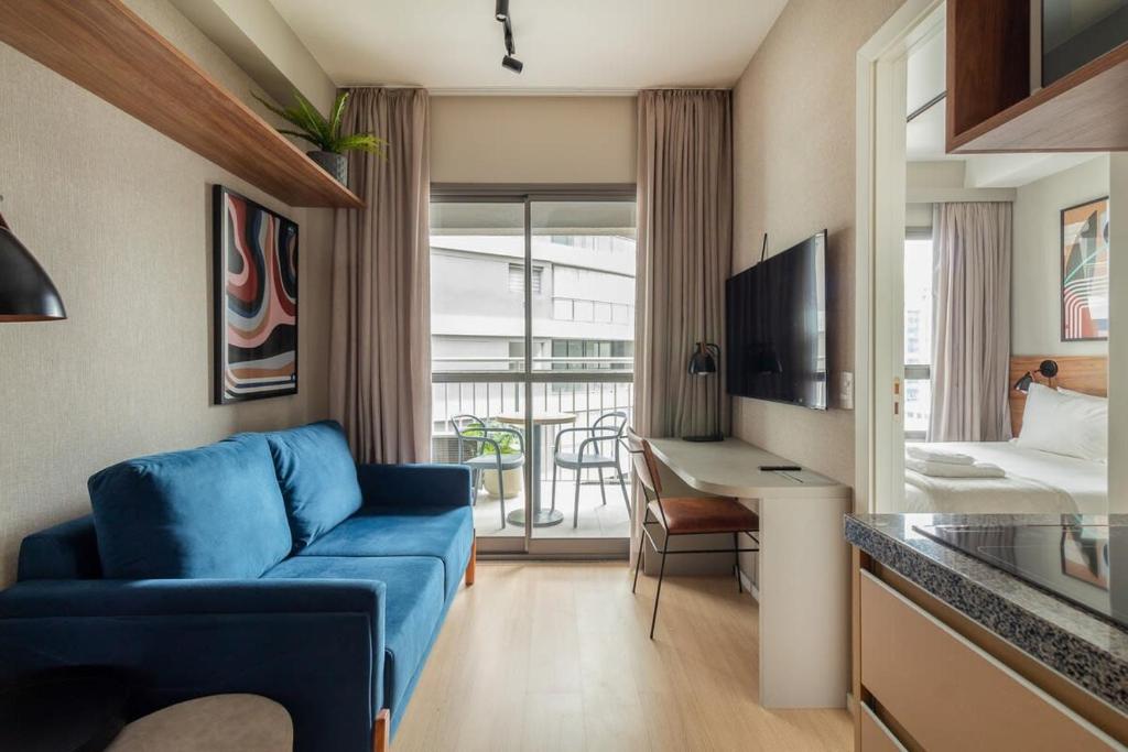 een woonkamer met een blauwe bank en een slaapkamer bij BHomy V Nova Conceição - Moderno e novo NX1017 in Sao Paulo
