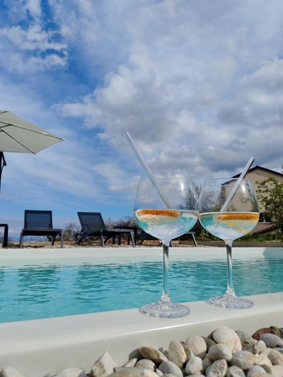 two wine glasses sitting next to a swimming pool at Apartment Aria in Lovran