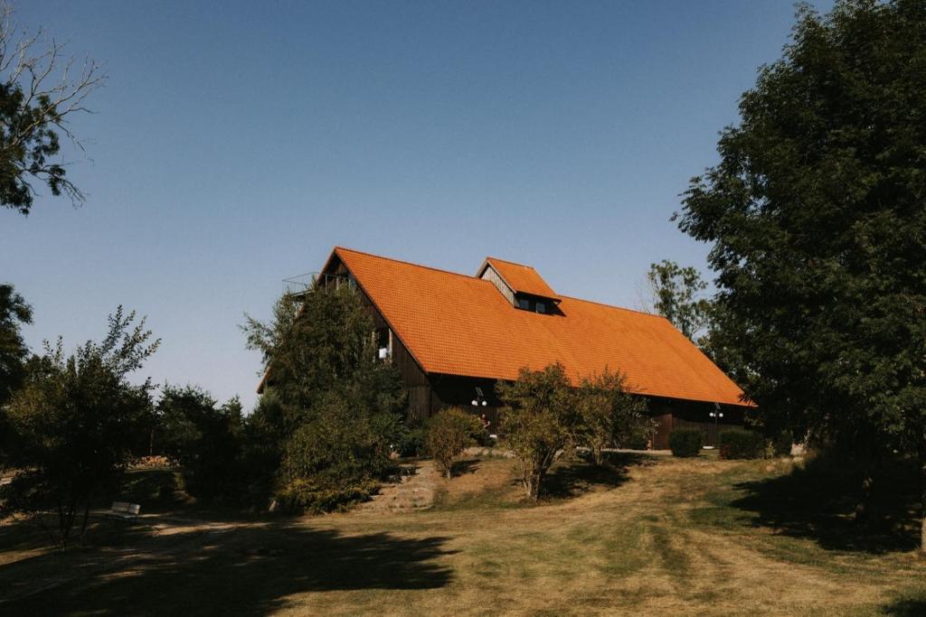 eine große Scheune mit orangefarbenem Dach in der Unterkunft Poganty - Jałownik in Giżycko