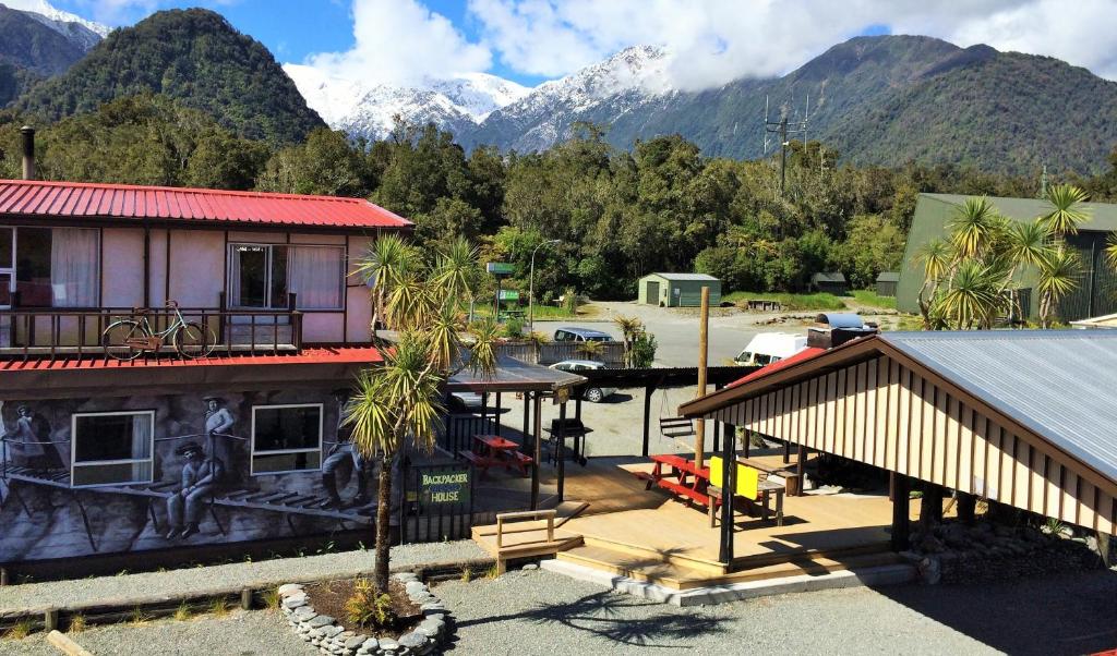 a resort with mountains in the background and a building at Chateau Backpackers & Motels in Franz Josef