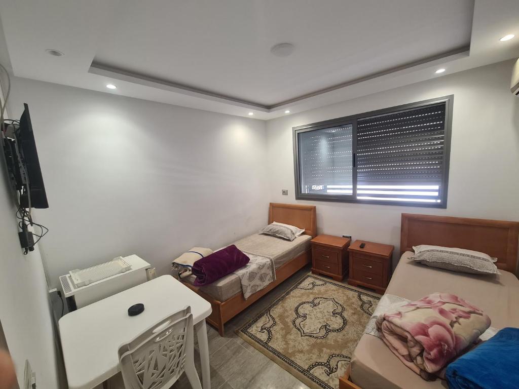 een kamer met 2 bedden, een bureau en een raam bij studio mami in Gabès