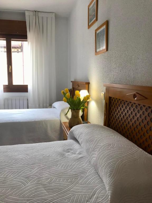 een hotelkamer met 2 bedden en een vaas met bloemen bij Elsoto in Quintana del Pidio