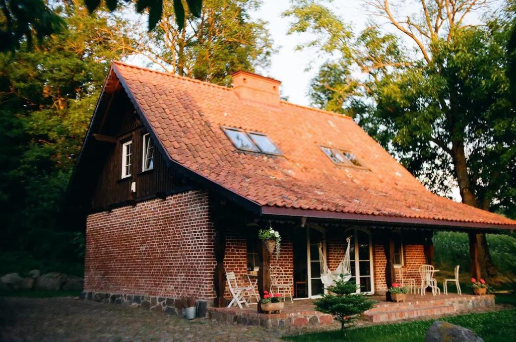 a small brick house with a red roof at Poganty - Mały Domek in Giżycko