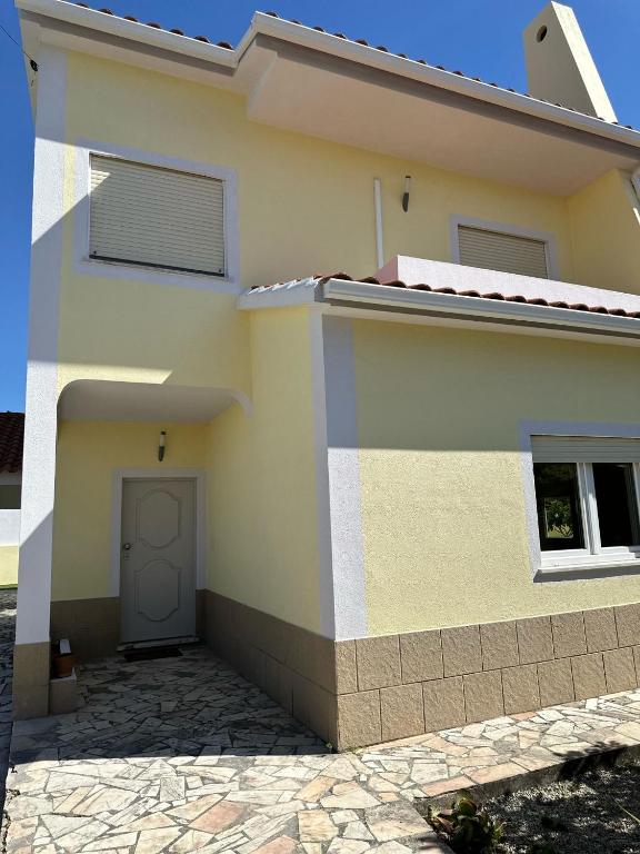 une maison jaune avec une porte sur son côté dans l'établissement Extraordinary Holiday House at Fernão Ferro!, à Fernão Ferro
