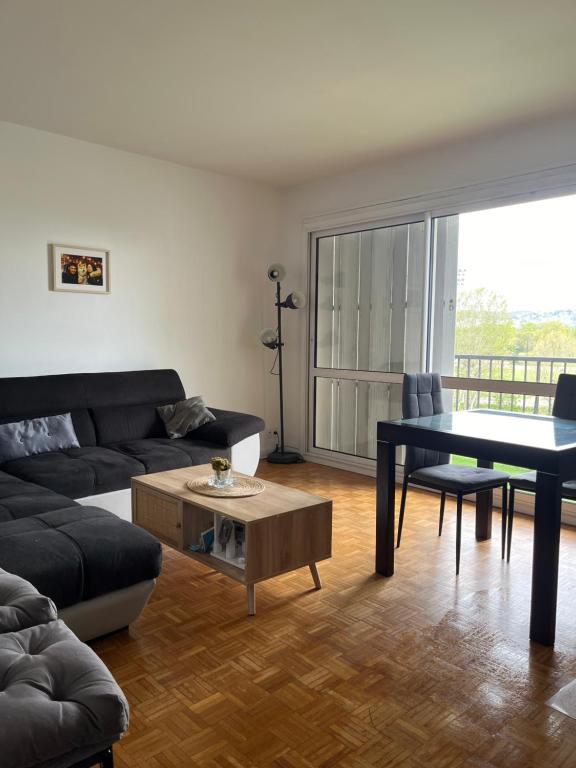 uma sala de estar com um sofá e uma mesa em Apartment in Calm Neighborhood em Eaubonne
