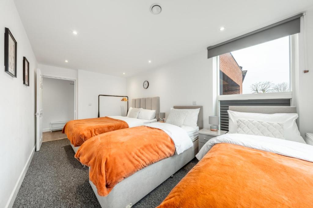 埃奇韋爾的住宿－London Edgware Station，一间卧室配有3张床,提供橙色床单