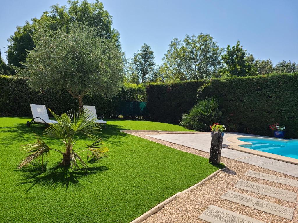 un jardin avec un banc et une piscine dans l'établissement Belle maison, à Bruguières