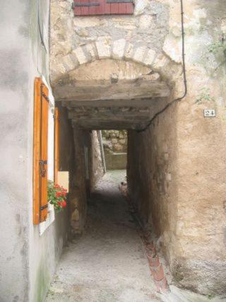 une ruelle avec un bâtiment en pierre et une fenêtre dans l'établissement Le Passadou, à Peyriac-de-Mer