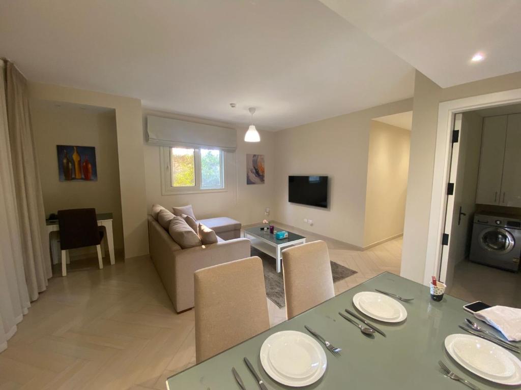 a living room with a couch and a table with chairs at Dyafa Suites Giza in Cairo
