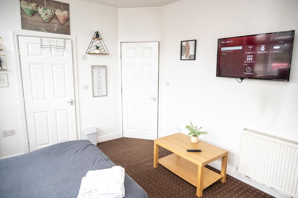 een slaapkamer met een bed en een tv aan de muur bij Bvapartments Deighton in Huddersfield