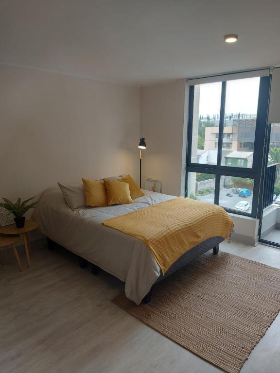 a bedroom with a bed and a large window at Hermoso departamento nuevo en el corazón de Independencia in Santiago