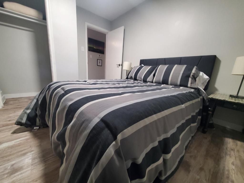 a bedroom with a large bed with a striped blanket at Modern Private 1BR Apt. w/Free Prkg + Fast Wi-Fi in Sault Ste. Marie