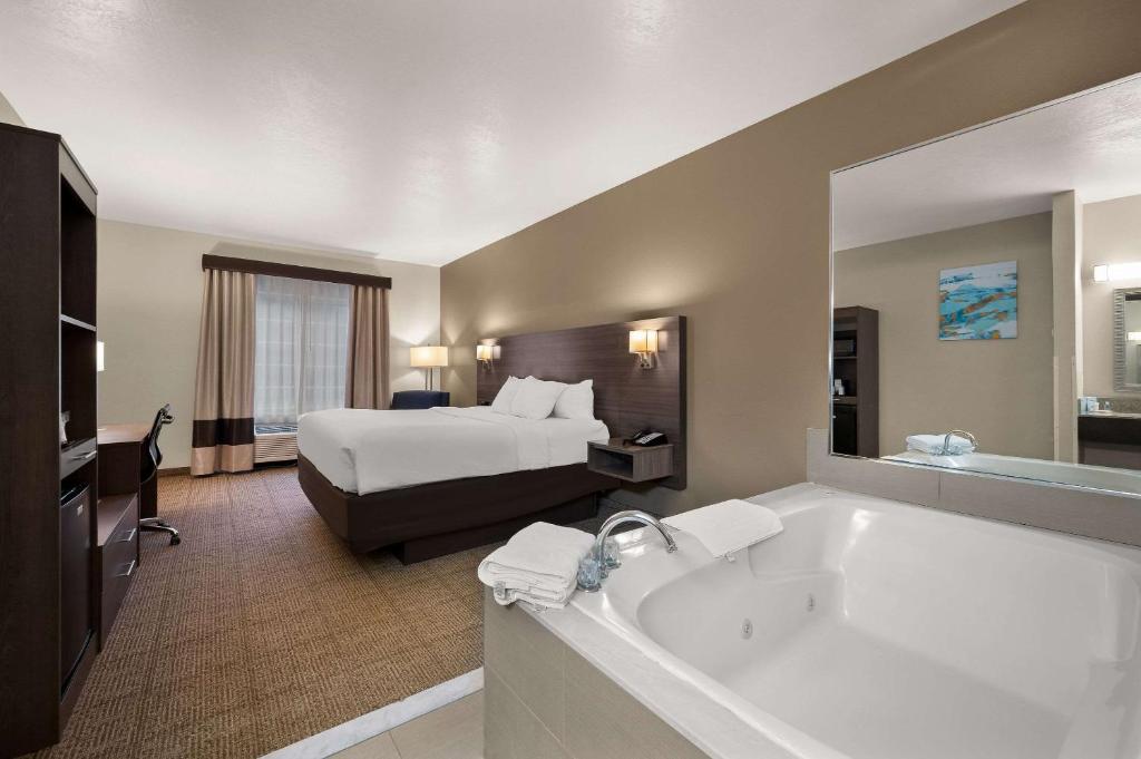 a hotel room with a bed and a bath tub at Comfort Inn & Suites in Fenton