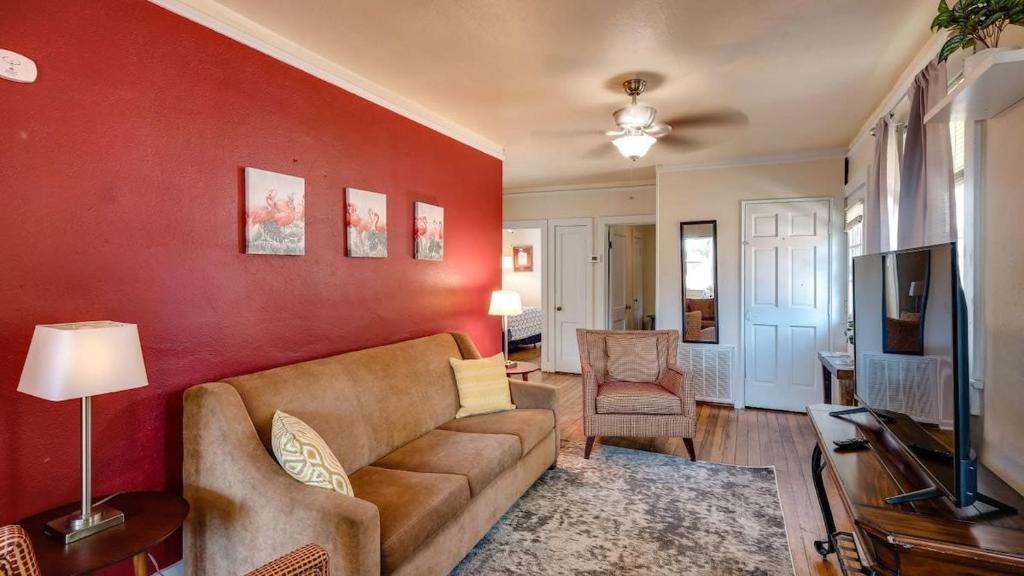 a living room with a brown couch and a red wall at Retro Rainbow at Herb River- Flamingo Flat #4 in Savannah