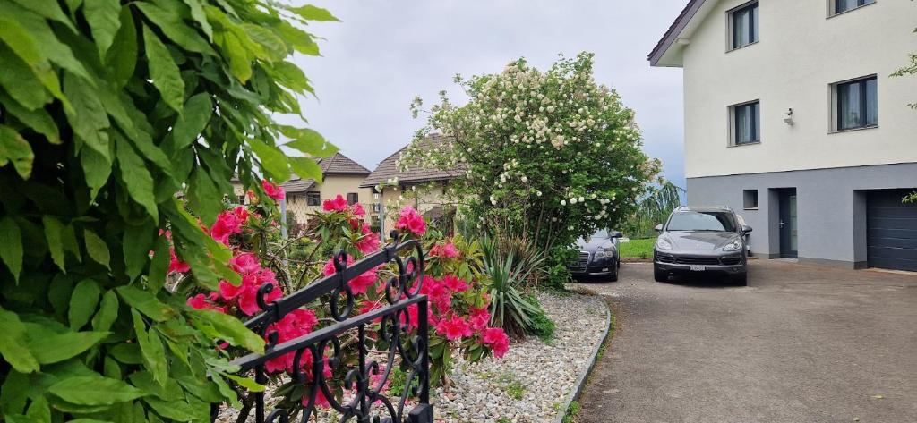 um carro estacionado ao lado de uma casa com flores cor-de-rosa em Coeur du Léman em Saint-Legier-La Chiesaz