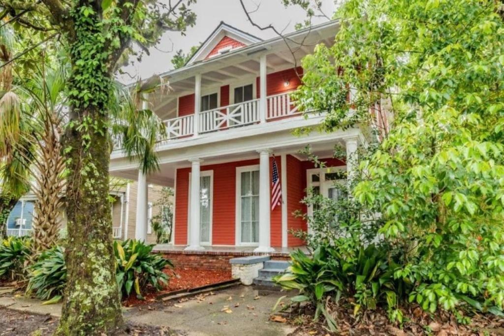 een rood huis met een Amerikaanse vlag erop bij Pretty Peach Palace-Historic, Mins to Downtown in Mobile