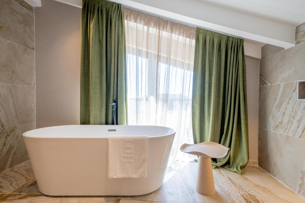 a bathroom with a tub in front of a window at Hotel Millennium by Aycon in Budva