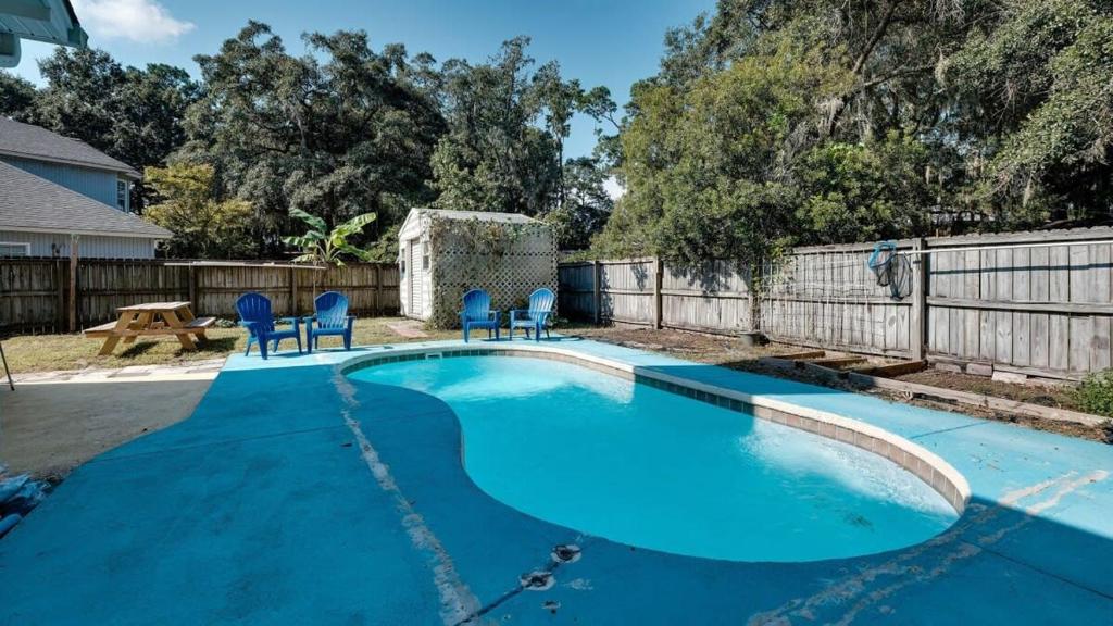 a swimming pool with blue chairs and a fence at Mins to Savannah-Peachy Pied-à-Terre in Savannah