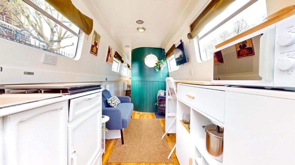 an rv kitchen with white cabinets and a blue chair at Executive houseboat in Little Venice in London