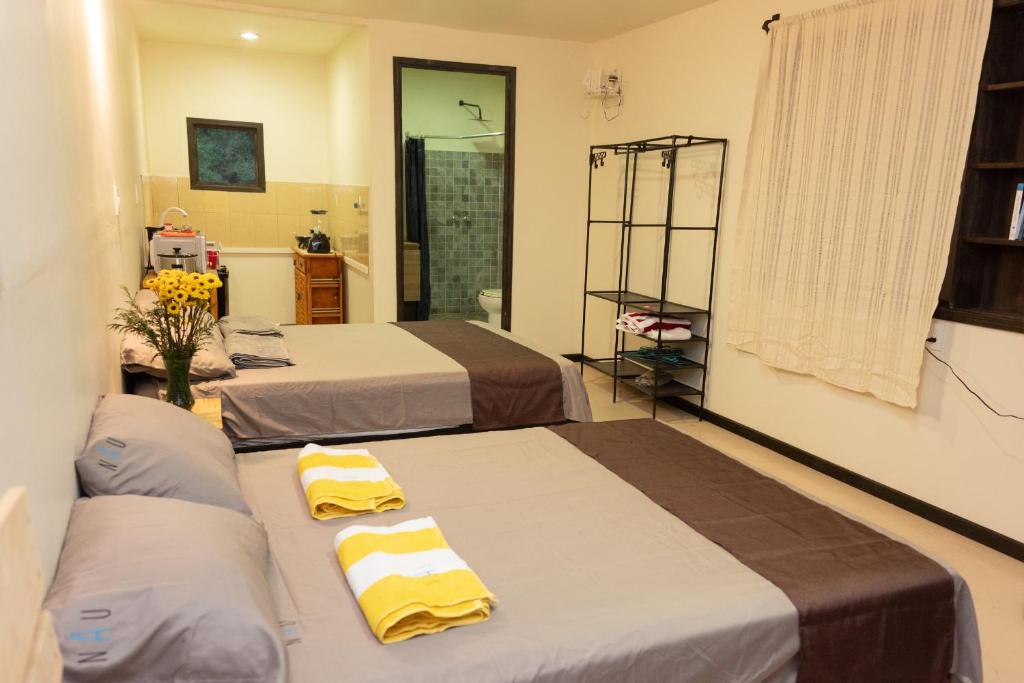 Dos camas en una habitación con toallas amarillas. en Casa NAU Mazunte, en Mazunte