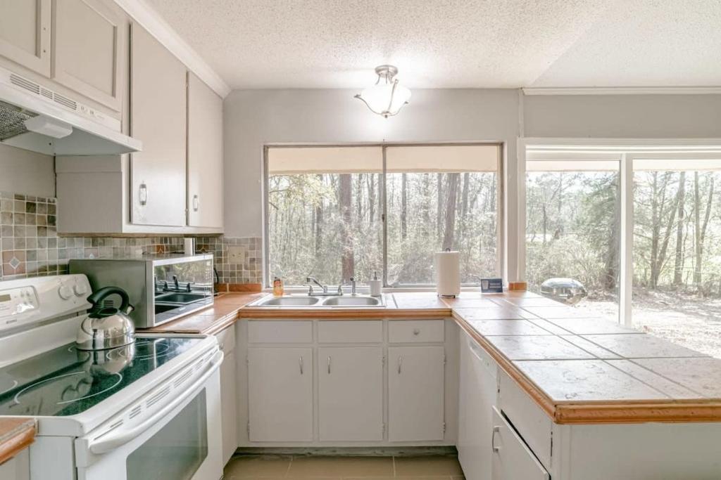 a kitchen with white cabinets and a large window at Parkhill Place- Mins from University of South AL in Mobile