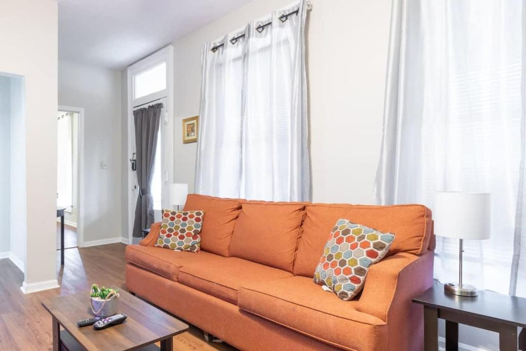 un sofá naranja en una sala de estar con ventanas en Wrap-Around Porch Uptown Stay-Pets Welcome!, en Columbus