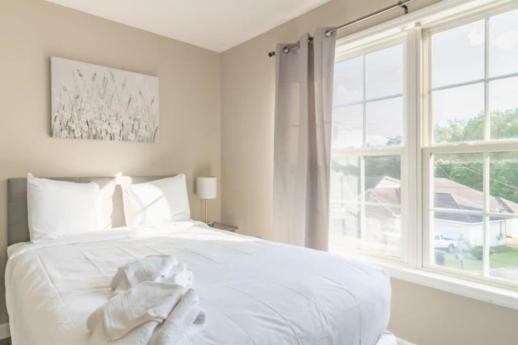 a white bed in a bedroom with a large window at Minutes to Benning Two-Story Oasis Benning Bliss in Columbus